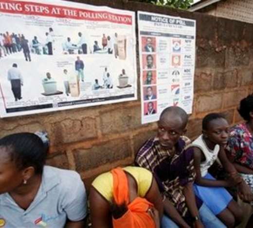 People sit under signs explaining the voting process as they wait for polls to open in Accra, Ghana, Sunday, Dec. 7, 2008. An estimated 12.4 million registered voters, roughly half the country s population of 23 million, will choose from one of eight candidates to succeed President John Kufuor, who is stepping down after two terms as required by law. (AP Photo/Rebecca Blackwell)