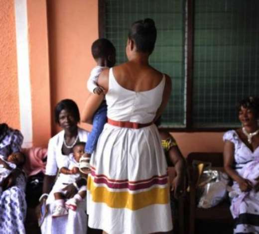 US First Lady Michelle Obama (C) holds a child while greeting new mothers during their participation in a maternal health program tour at LA General Hospital in Accra, Ghana 11 July 2009. President Obama is spending the day in Ghana addressing Parliament, visiting a maternal health program and touring Cape Coast Castle. EPA/SHAWN THEW
