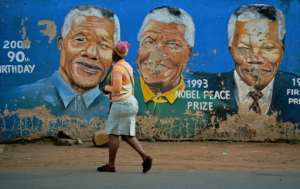 A resident of Soweto, where Nelson Mandela used to live, walks past a mural of the late anti-apartheid hero after his death on December 5, 2013.  By Carl DE SOUZA (AFP/File)