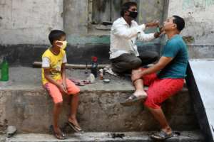 A barber wearing a facemask attends to a customer in Kolkata during a government-imposed nationwide lockdown.  By Dibyangshu SARKAR (AFP)