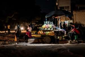 A fruit vendor is seen during a power outage in Westfield, The Gambia.  By MUHAMADOU BITTAYE (AFP)