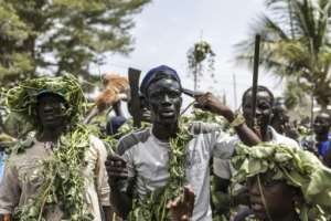 A hunter adorned with protective vines points a pistol at his head during a hunt procession.  By PATRICK MEINHARDT (AFP)