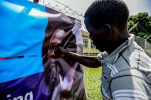 A man punches a banner bearing a picture of Dominic Ongwen.  By ISAAC KASAMANI (AFP/File)