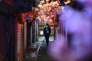 A man wearing a face mask walks along Omoide Yokocho in Tokyo.  By Philip FONG (AFP)