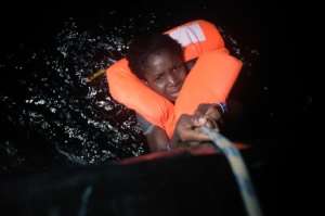 A migrant holds onto a rope during a rescue operation some eight nautical miles off Libyas Mediterranean coastline on October 12, 2016