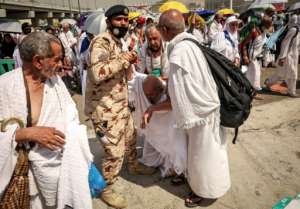 A policeman and other pilgrims help a worshipper affected by the scorching heat.  By FADEL SENNA (AFP)