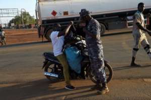 A policeman searches a vendor on a motorbike at the Togo-Burkina Faso border in Cinkasse.  By PIUS UTOMI EKPEI (AFP)