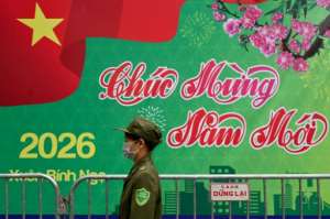 A security guard walks past a New Years greeting banner in Hanoi.  By Nhac NGUYEN (AFP)