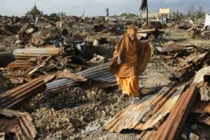 A woman salvages burnt iron sheets where her home was destroyed.  By Tony KARUMBA (AFP)