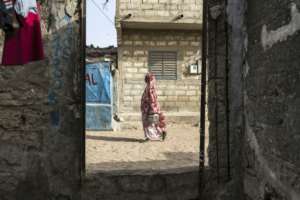 A woman walks on a street in Mbour, a coastal city which like other Senegalese fishing areas has had multiple residents migrate.  By PATRICK MEINHARDT (AFP)