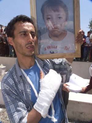 A wounded Berber man, pictured in May 2001, holds the picture of a 13-year-old boy who was shot dead in clashes in Takriet, near Bejaia, in the Kabylie region.  By - (AFP/File)