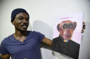 Agbaje at his studio, holding a painting Rain Priest.  By PIUS UTOMI EKPEI (AFP)
