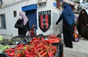 Algerian women walk past a shop bearing the colours of the Union Sportive Medina dAlger (USMA) football club in the old Soustara neighbourhood of Algiers on October 11, 2016
