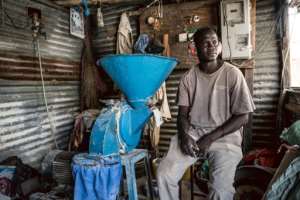 Amadou Gaye, 40, cannot run his millet milling machine without power at his shop in Sukuta.  By MUHAMADOU BITTAYE (AFP)