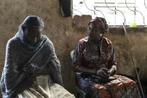 Aminata Boye (R) visits with another woman at her home in Mbour, Senegal.  By PATRICK MEINHARDT (AFP/File)
