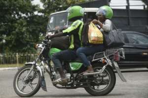 An ORide driver, decked out in bib and helmet, takes a passenger through the Lagos gridlock.  By PIUS UTOMI EKPEI (AFP)