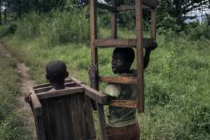 Boys remove furniture from a school taken over my M23 fighters in eastern DR Congo in April.  By ALEXIS HUGUET (AFP)