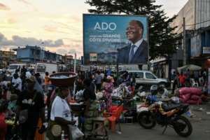 Customers and vendors stand next to a billboard for Ivorian President and presidential candidate Alassane Ouattara.  By Issouf SANOGO (AFP)
