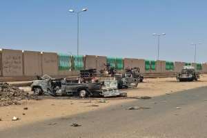 Destroyed vehicles line the street in southern Khartoum.  By - (AFP)