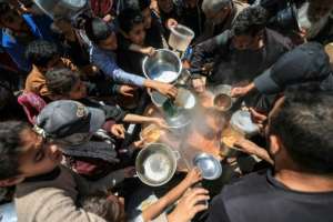 Displaced Palestinians receive food from a charity kitchen at a refugee camp in the central Gaza Strip in April 2026.  By Eyad Baba (AFP)