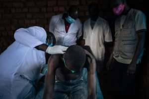 Doctors from Uketys team look for traces of onchocerciasis on a study participant in the village of Kanga.  By ALEXIS HUGUET (AFP)