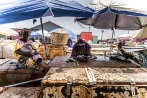 Fishmongers rest on top of their ice boxes at the fish landing in the town of Tanji, where ice is increasingly rare.  By MUHAMADOU BITTAYE (AFP)
