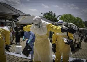 Health workers are doused with disinfectant after contact with the body of one presumed Ebola fatality.  By Glody MURHABAZI (AFP)