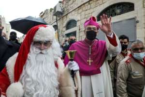 In Bethlehem, the Latin Patriarch of Jerusalem, Archbishop Pierbattista Pizzaballa, arrived to attend Christmas celebrations -- walking alongside a man dressed as Father Christmas, or Santa Claus.  By HAZEM BADER (AFP)