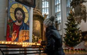 In Germanys capital Berlin, a worshipper lights a candle in St Marys church ahead of an outdoor mass on Christmas Eve.  By John MACDOUGALL (AFP)