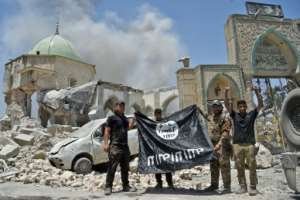 In this file photo taken on June 30, 2017, members of the Iraqi Counter-Terrorism Service (CTS) with a flag of the Islamic State held upside down, outside the destroyed Al-Nuri Mosque in Mosuls old city.  By FADEL SENNA (AFP/File)