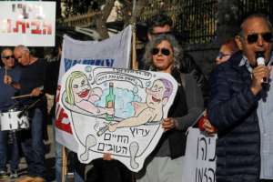 Israeli protesters in mid-February hold up a cartoon of Prime Minister Benjamin Netanyahu and his wife Sara luxuriating in a jacuzzi tub. Another man holds a sign reading Bibi (go) home! in Hebrew