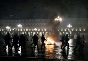 Italian police officers stand in front of a wheelie-bin on fire during a protest in downtown Turin..  By Marco BERTORELLO (AFP)