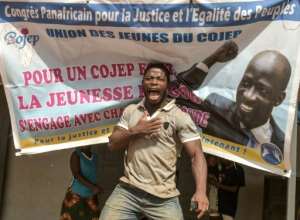 Jubilation: A man in Abidjan celebrates in front of a campaign poster of Charles Ble Goude after the ICC announced the acquittal. By SIA KAMBOU (AFP)