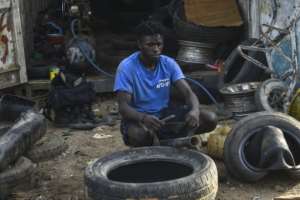 Mory Soumaoro fixes a tyre at his workshop in Liberias Montserrado County.  By MATTHEW JACOBS (AFP)