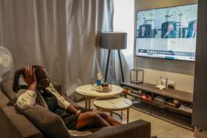 Mulumbwa Luchen settles in front of the television to binge the Madlanga commission.  By PHILL MAGAKOE (AFP)
