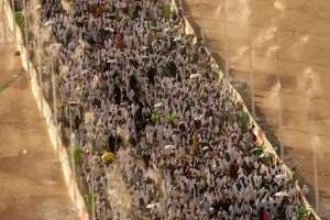 Muslim pilgrims walk under mist dispensers as they arrive to perform the symbolic stoning of the devil ritual during the annual hajj pilgrimage in Mina on June 16, 2024.  By Fadel SENNA (AFP/File)