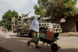 Nigerian troops patrol Banki where at least 80 girls were brought after the government negotiated the release of 82 of over 200 schoolgirls kidnapped by Boko Haram