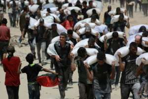 Palestinians carrying sacks of flour after trucks carrying humanitarian aid entered northern Gaza.  By BASHAR TALEB (AFP/File)