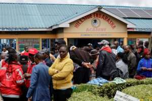 Parents and members of the community gather outside the school after the devastating blaze.  By SIMON MAINA (AFP)
