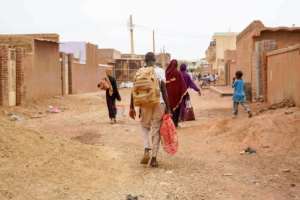 People carrying their belongings walk down on a street in Omdurman, the capitals twin city in war-torn Sudan, on May 29, 2023.  By - (AFP)