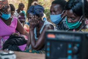 People from Lukodi gather around the radio to listen to the verdict.  By Sumy Sadurni (AFP)