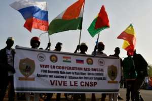 People in Niamey wave flags from Russia, Niger, Burkina Faso and Mali during a gathering to celebrate the withdrawal of the three African states from the Economic Community of West African States (ECOWAS) in January 2025.  By Boureima Hama (AFP/File)