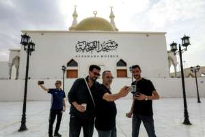 People pose for a group selfie outside the Sahaba Mosque in Derna.  By Abdullah DOMA (AFP)