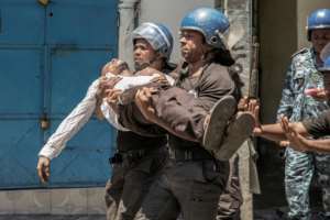 Police take away a plainclothes policeman injured in Monday's clashes. By GIANLUIGI GUERCIA (AFP)