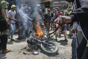 Protestors torch a motorbike belonging to suspected hired goons during protests in July 2024.  By Tony KARUMBA (AFP)