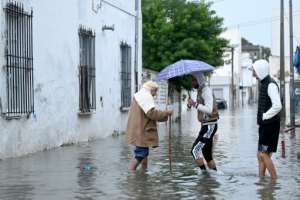 A man carries a bag of bread as he wades through flood waters, in La Goulette near the capital Tunis, on Januray 20, 2026. Flooding across Tunisia has killed three people, authorities said January 20, with one official reporting a critical situation as parts of the North African country experienced their heaviest rainfall in more than 70 years..  By FETHI BELAID (AFP)
