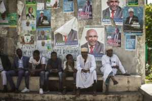 Supporters of the opposition Juwa Party sit beneath campaign posters, waiting for a rally in a village near Moroni. By GIANLUIGI GUERCIA (AFP)