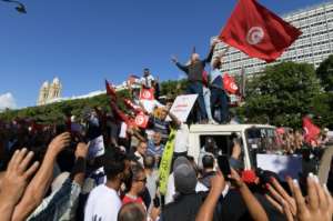 Tunisians raise national flags.  By FETHI BELAID (AFP)