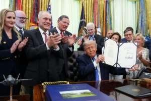 US President Donald Trump holds up his latest deportation bill, the Secure America Act, after signing it in the Oval Office last month.  By Ken Cedeno (AFP)