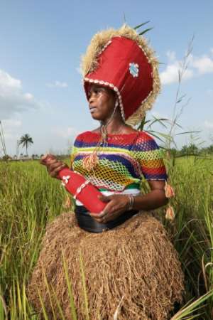 Yealie Kabba, a Bondo society member in Waterloo, wears a red hat with a mirror called a kashak and holds a red bottle filled with spiritual wine, used for purification.  By LYNN ROSSI (AFP)